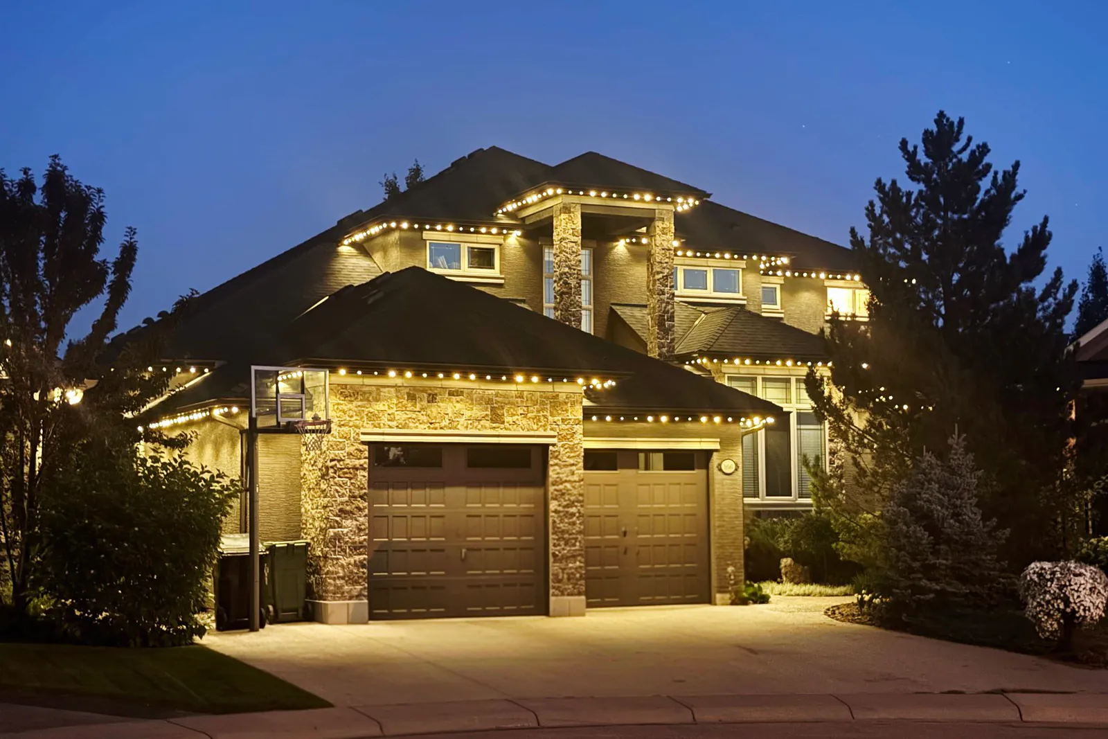 Two-storey Calgary home at dusk, LED trim glowing warm white along the rooflines and gable peaks